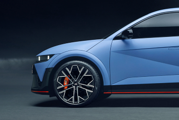 Front side view of a blue Hyundai N model highlighting the alloy wheel with red brake caliper.