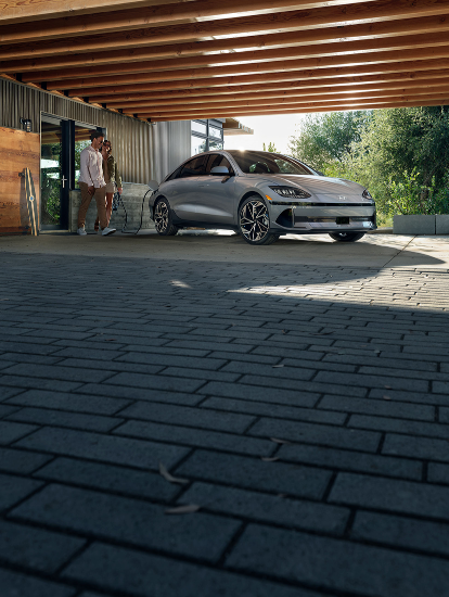Couple walking near a Hyundai EV charging at home.